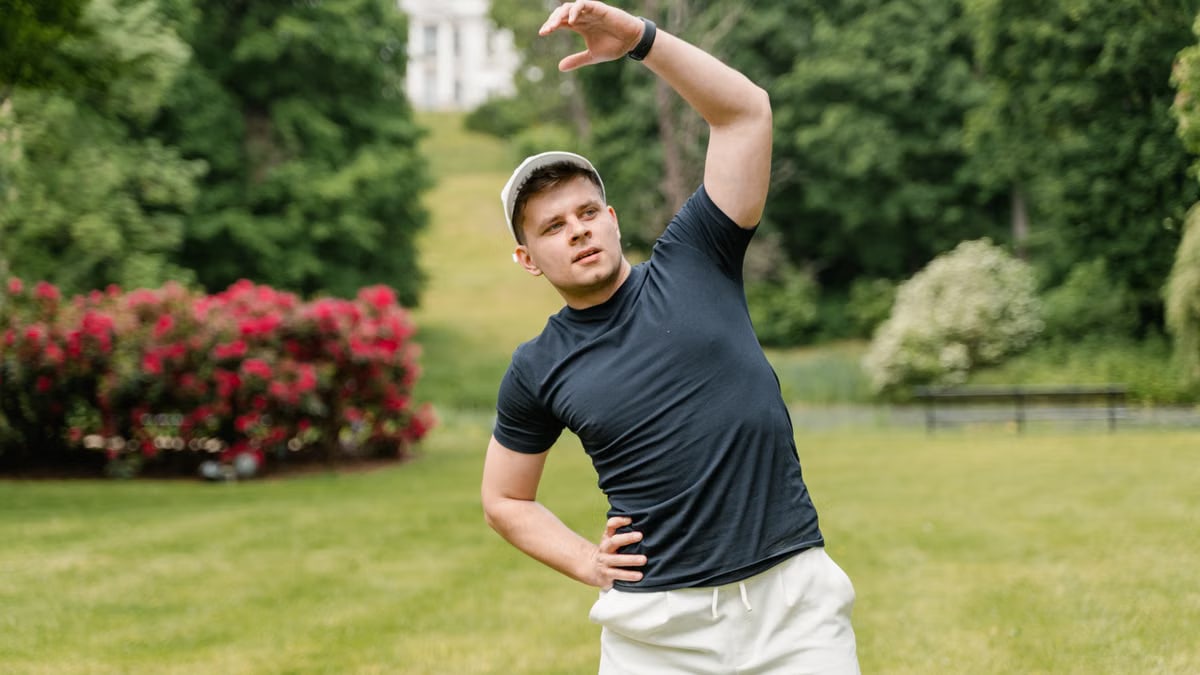 Man stretching in a park wearing a black shirt and white shorts, embracing a healthy lifestyle.